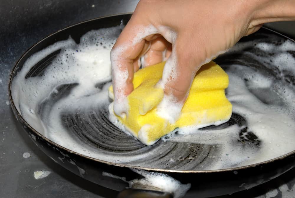 Cropped image of hands washing frying pan with sponge and soap