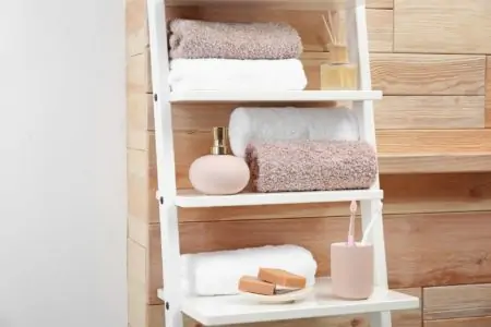 Towels, toiletries and soap dispenser on shelves in bathroom