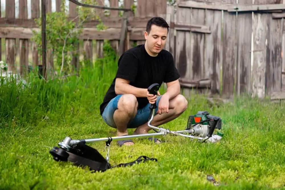 Man holding a gas trimmer in the garden