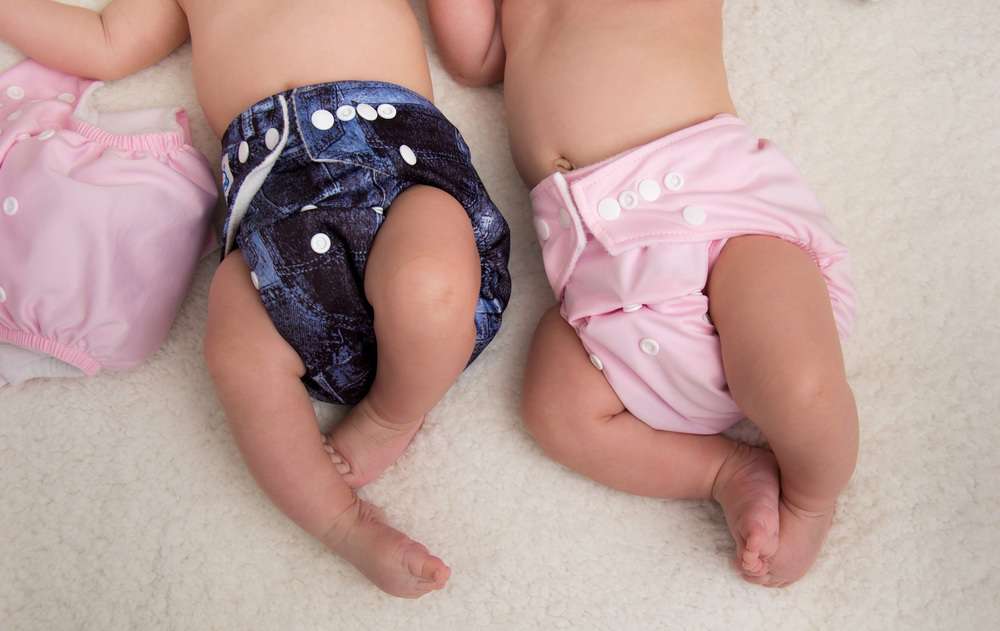 Babies lying on bed wearing eco-friendly cloth diapers