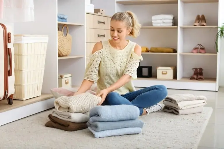 Woman folding jackets and stacking them on the floor