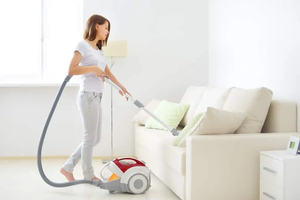 Woman cleaning couch using a vacuum cleaner