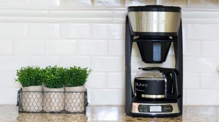 Bun Coffee Maker on countertop with potted plants on the side