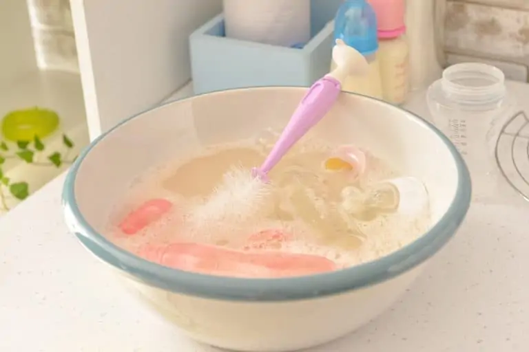 Baby bottles, nipples, and brush soaked in water with dishwashing soap