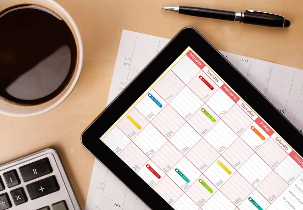 Tablet pc showing calendar on screen with a cup of coffee on a desk