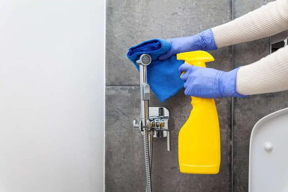 Hands in blue protective gloves cleaning hygienic shower