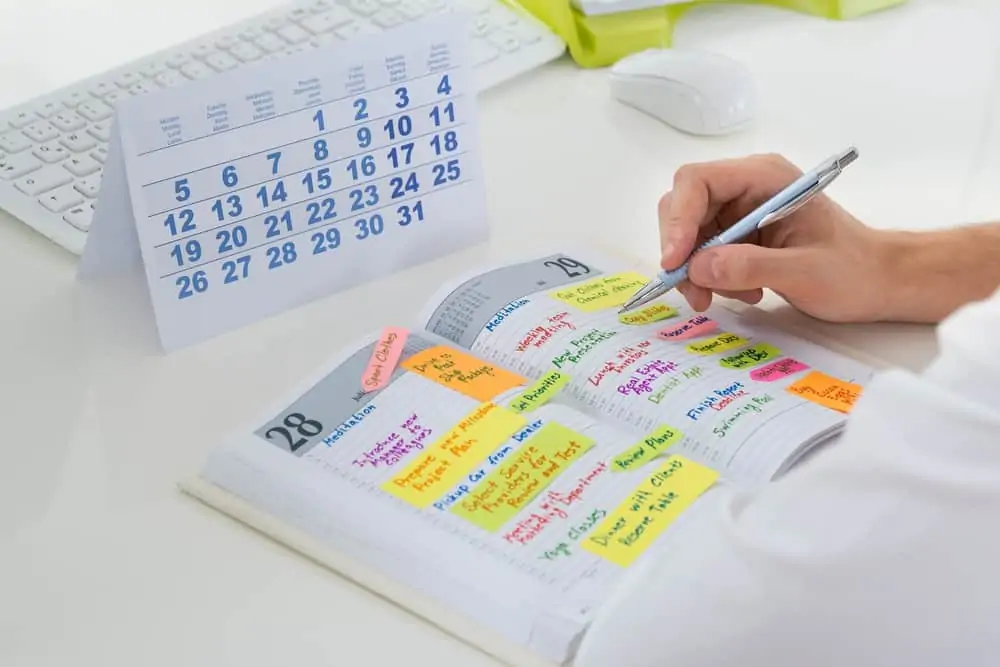 Close-up image of a man's hand writing on a planner