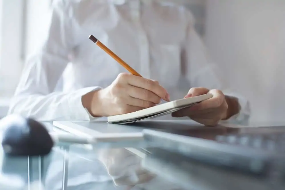 Woman's hand using a pencil noting on notepad