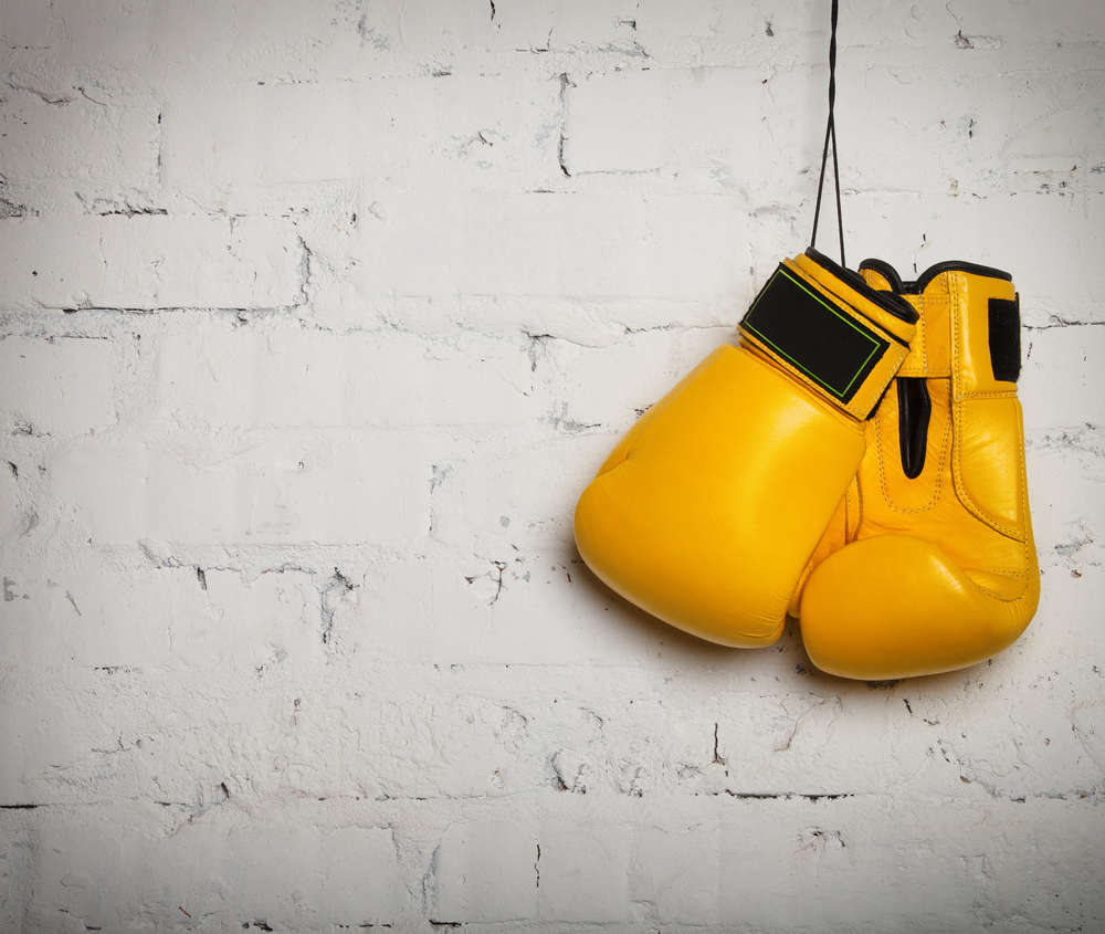 Pair of yellow boxing gloves hanging on a wall