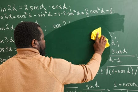 African-American math teacher wiping chalkboard using microfiber cloth