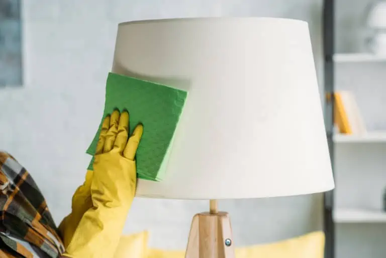 Cropped image of woman wiping lampshade with cloth