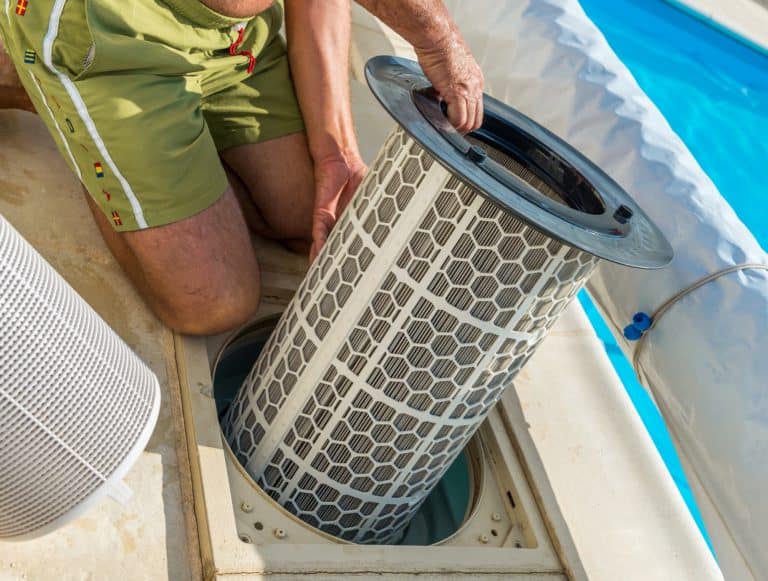 Man removing filter cartridges from the pool filter tank