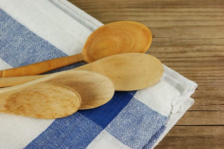 Wooden spoon and dish cloth on wooden table