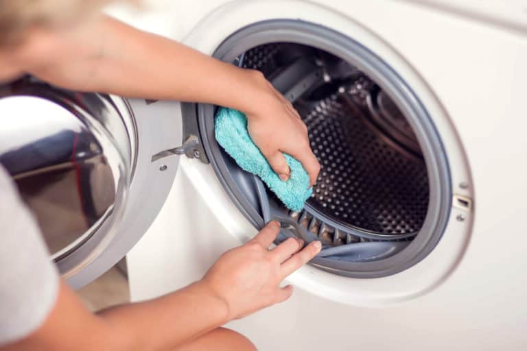 Dirty washing machine with mold being wiped with a cloth