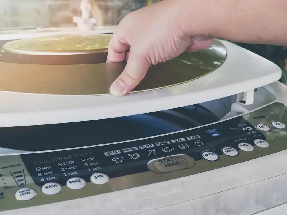 Man holding top load washer lid and opening it for laundry