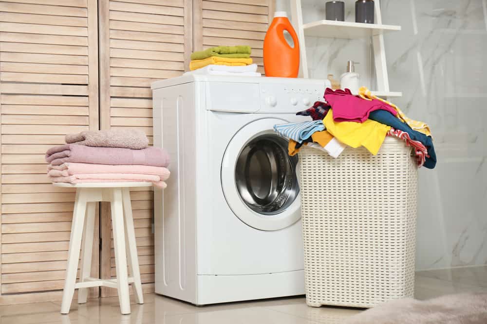 Basket of laundry, towels on the chairs, and soap in laundry room