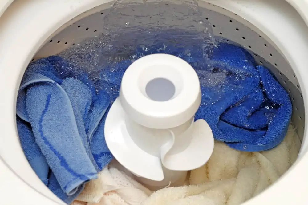 Washing machine being filled with water covering the full load of linens