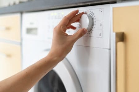 Hand of a woman selecting wash program of a front load washer
