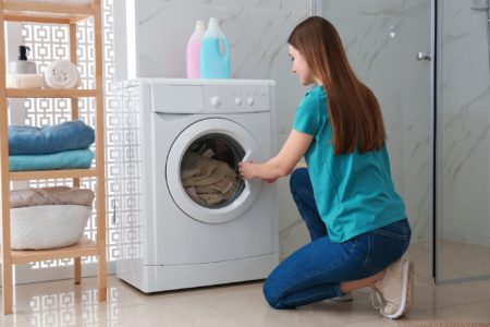 Woman sitting near washing machine in laundry room
