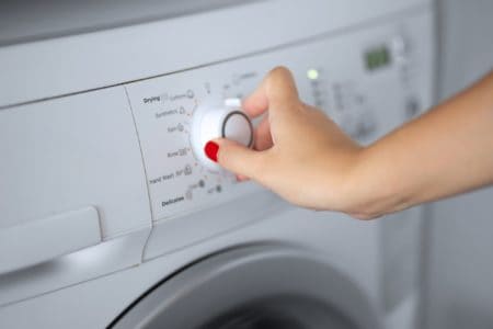 Hand of a woman sets the wash cycle for the washing machine