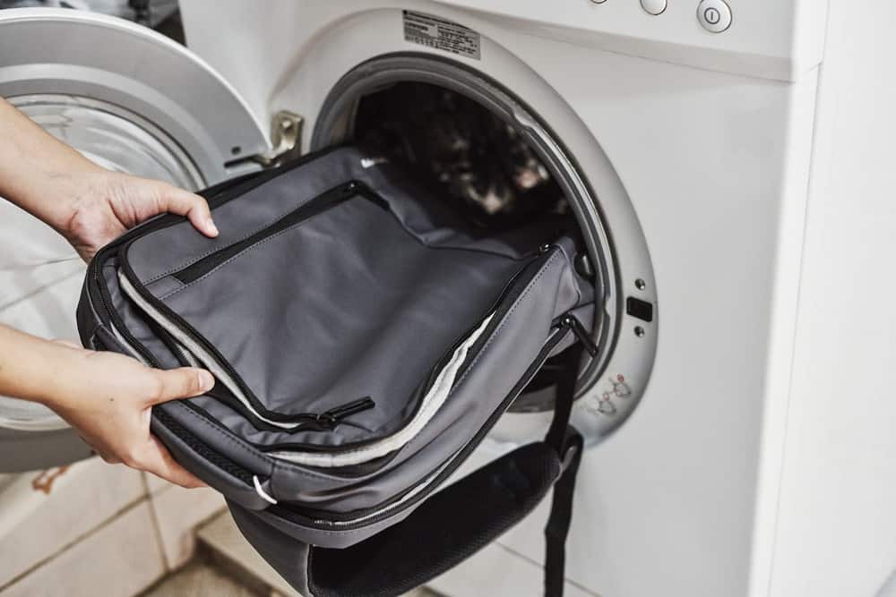 Person places black backpack in washing machine