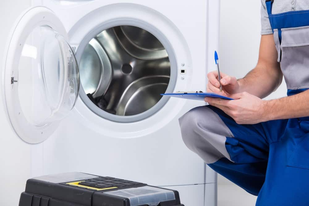 Repairman writing on a blue board in front of a front load washer