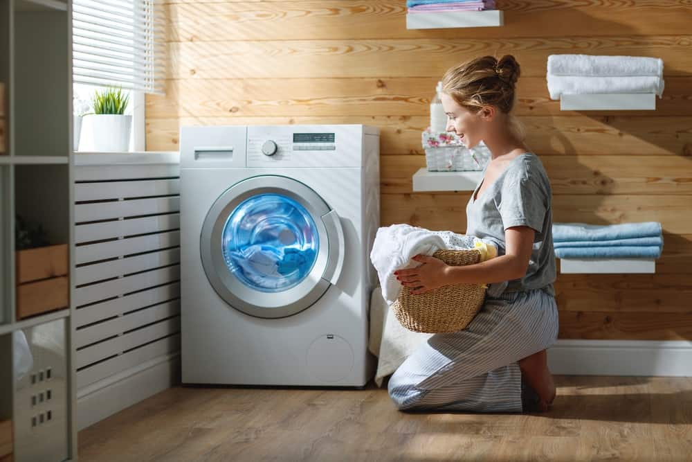 Smiling woman in laundry room holding basket of clothes
