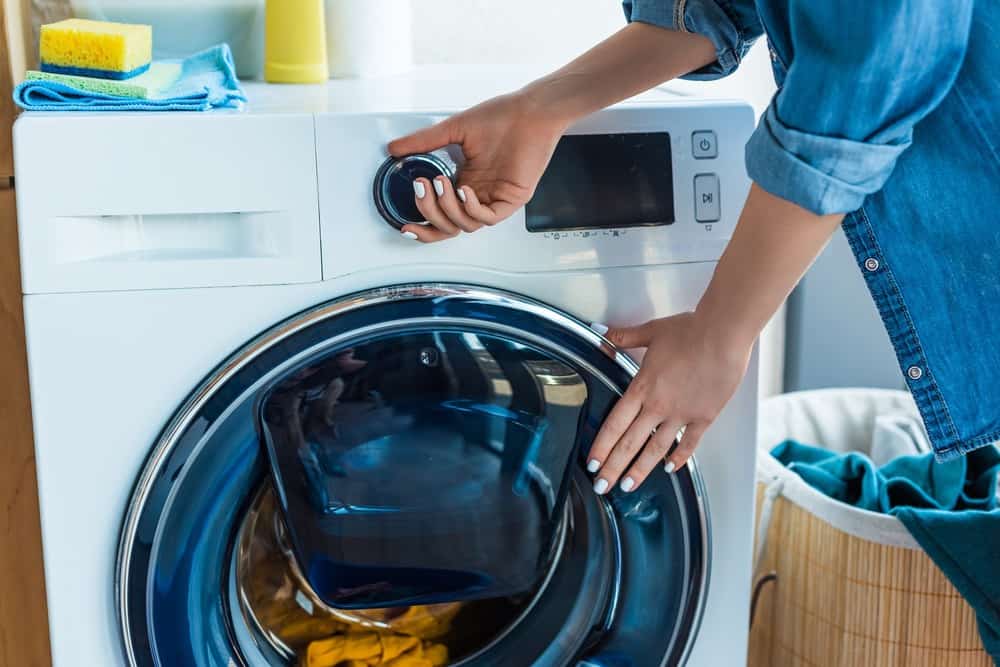 Woman using front load washing machine