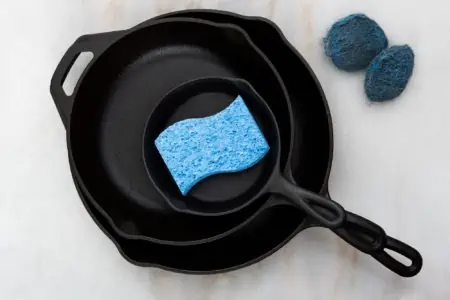 Cast iron skillet with blue sponge on the table