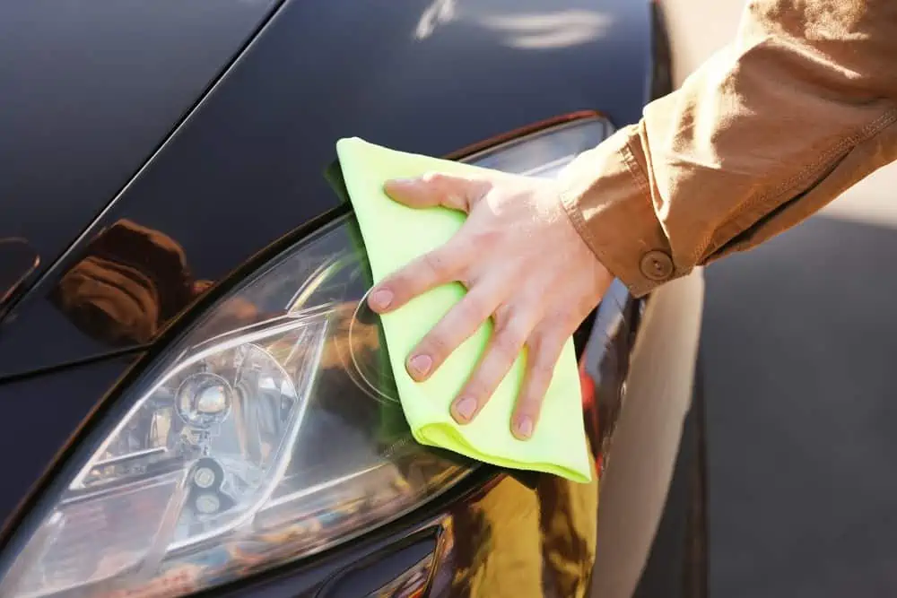 Male hand wiping the headlights using microfiber cloth