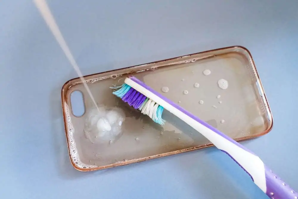 Cleaning silicone phone case with toothbrush, foam and soap