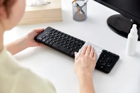 Woman wiping keyboard with wipes
