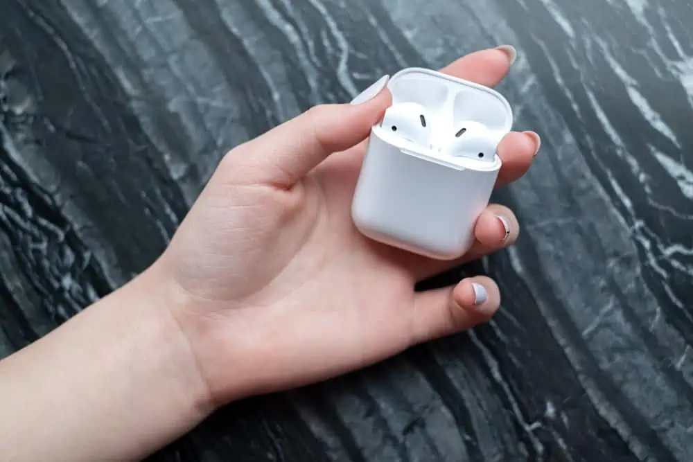 Female hand holding white charging airpods case