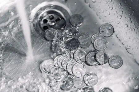 Washing coins in the sink with continuous flowing water