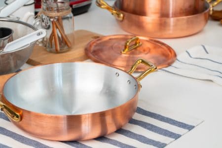 Copper cookware on placemat on top of the table with other utensils