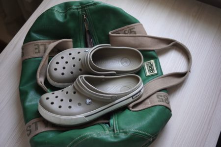 Pair of crocs on green duffel bag