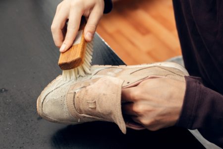 Worker cleaning suede shoes with a soft bristled brush