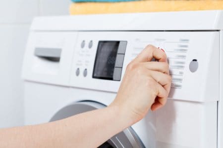 Woman's hand turning on the front load washing machine