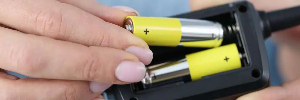 Female hands inserting batteries in battery terminal