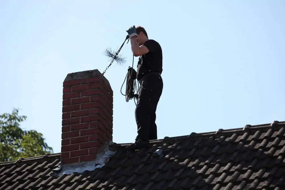Man inserting brush into chimney