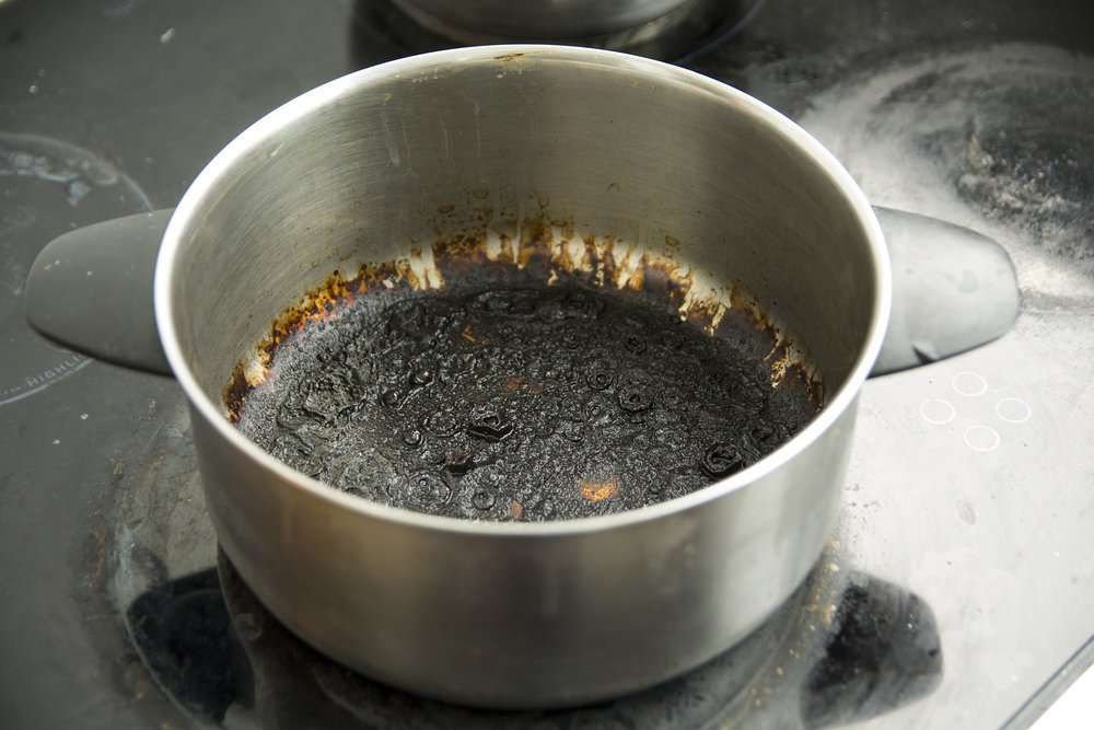 Burnt stainless pot on top of electric gas stove