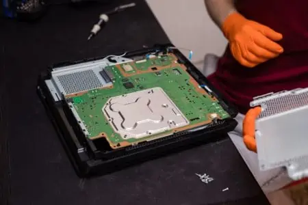 Man in orange gloves parses the PlayStation console