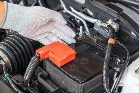 Technician wearing gloves checking battery car terminal