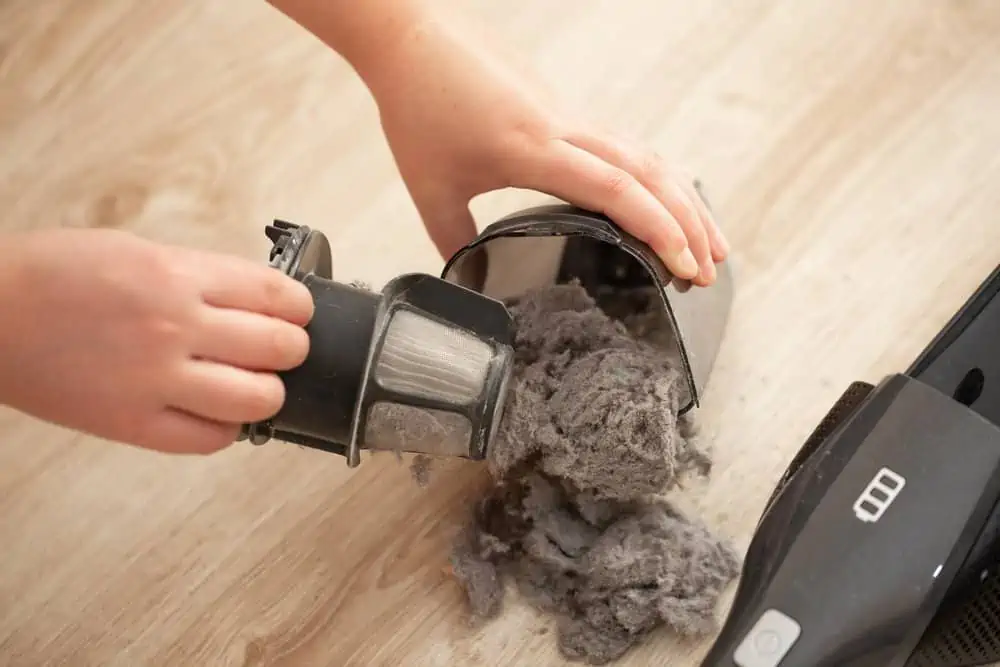 Cropped photo of woman's hand taking out massively clogged filter of vacuum cleaner