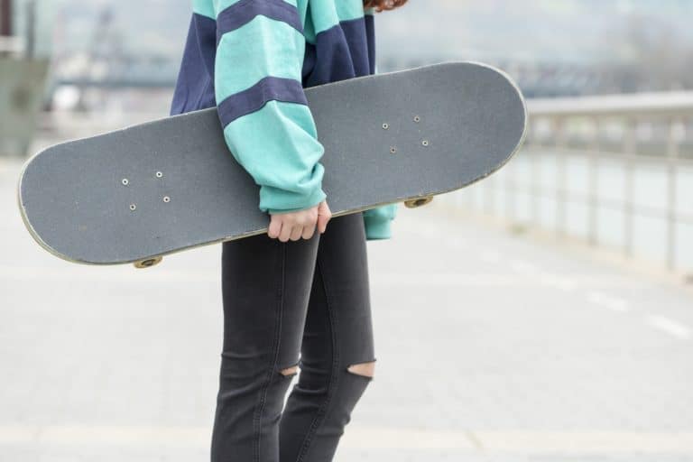 Close-up hand holding skateboard on the street