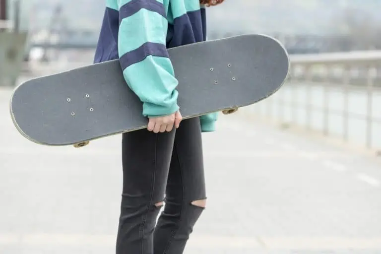 Close-up hand holding skateboard on the street