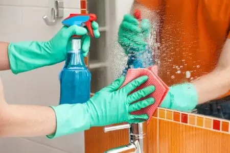 Man cleaning mirror with rag and spray cleaner