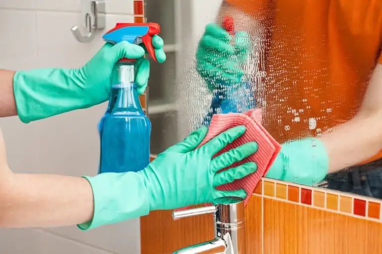 Man cleaning mirror with rag and spray cleaner