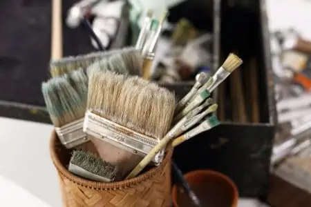 Multiple paint brushes in wooden cylinder holder