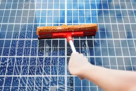 Close-up photo of person's hand cleaning solar panel